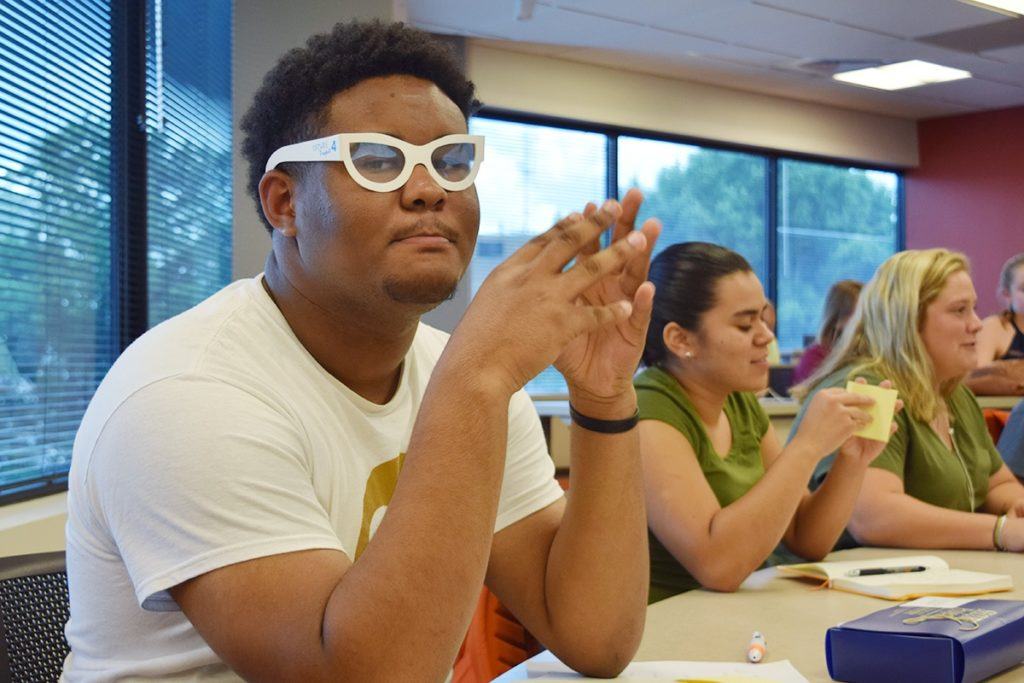 Male student with glasses participates in classroom session