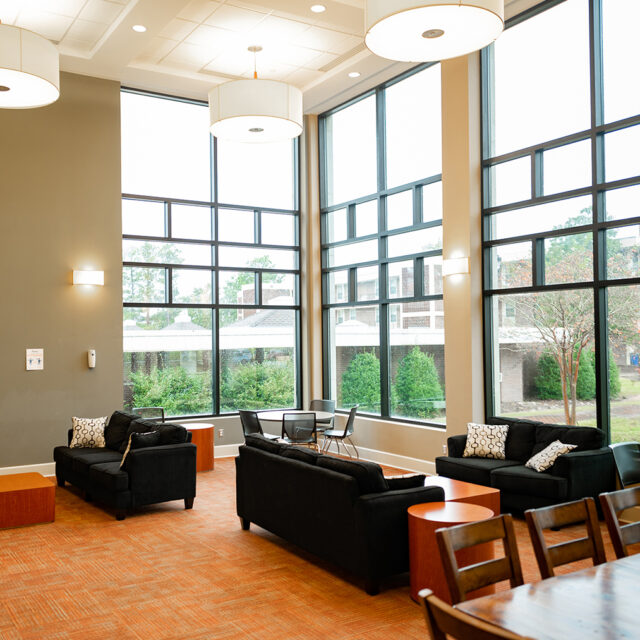 The common area in Pat Barker Hall includes several cozy sofas and floor-to-ceiling windows for ample light.