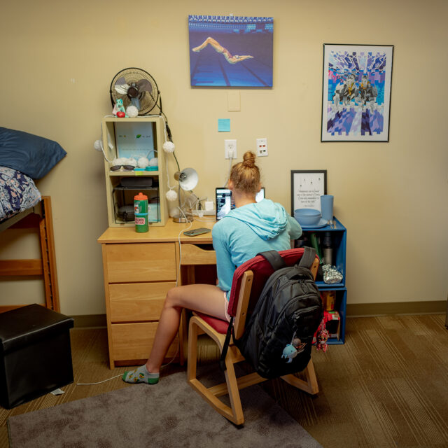 Female student studies at her laptop inside Burkot Hall