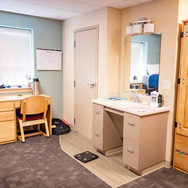 Image of a bedroom inside Jones Hall including a bed, desk, vanity area and wardrobe.