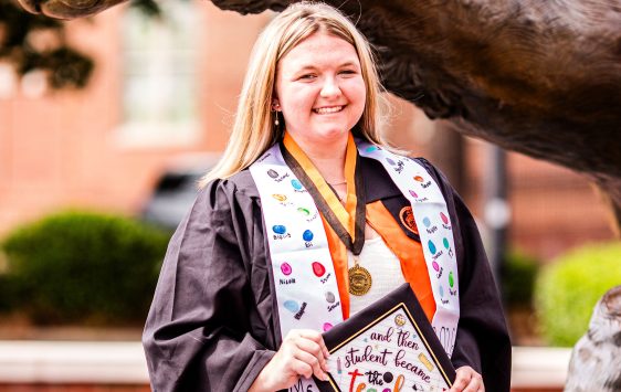 Portrait of Mackenzie Rusak, student, holding diploma.