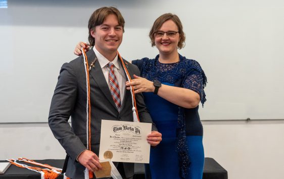 Zane House posing with diploma in classroom