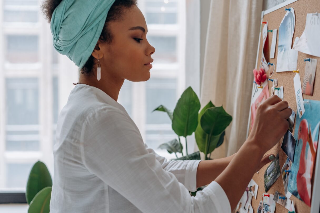 A young woman pins inspiration to a bulletin board.