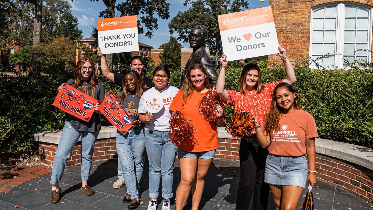 Students with giving day signs around the statue of JA Campbell