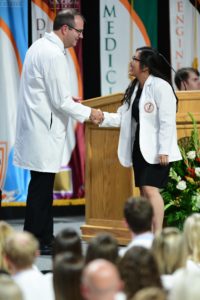 Dr. Adams shaking hand of student