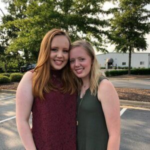 Sisters Savannah and Summer Gaskins stand in the Convocation Center parking lot, smiling and hugging.