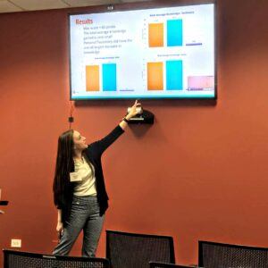 female student points to board during presentation
