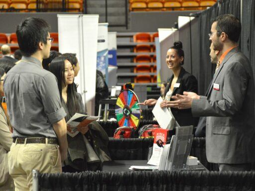 students surround a booth at Career fair on the floor of Gore Arena