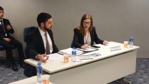 A male student on the left and a female student on the right sit at a table at the Vis competition in Hong Kong and appear to go over their notes.