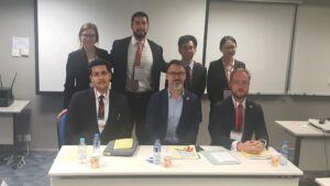 Four student advocates stand behind their judges seated at a table at the Vis Competition in Hong Kong.