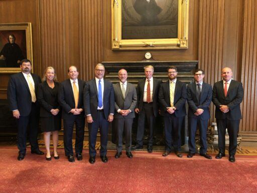 Photo of alumni gathered standing in front of a fireplace in a U.S. Supreme Court dining room with Dean Rich Leonard in the middle