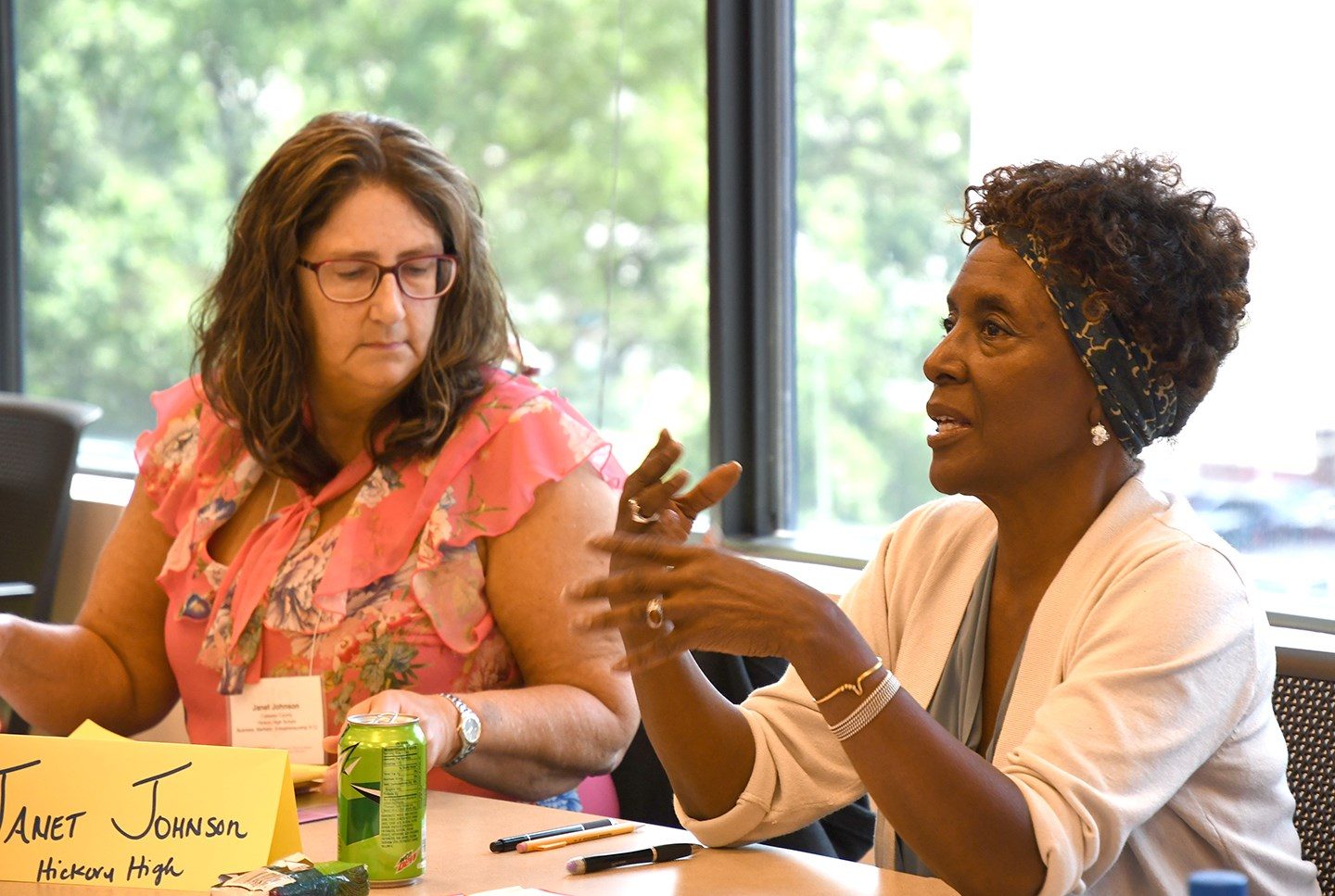 two women gesture as they ask questions in class