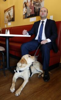 Photo of Cody Davis 18 and his service dog Clark looking up at him