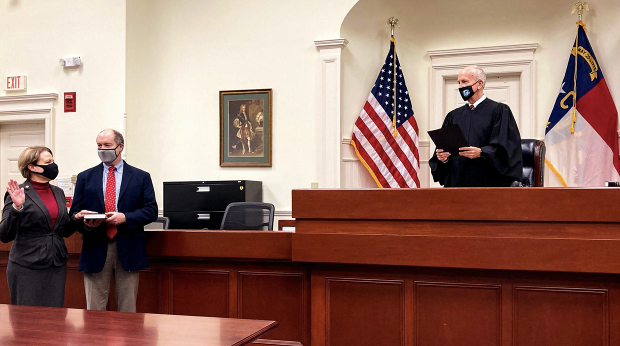 Photo of Chief Judge Donna Stroud (left) stands with her husband, J. Wilson Stroud, while Chief Justice Paul Newby administers her oath of office.