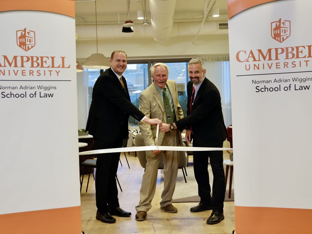 Photo of the Veterans Law Clinic Ribbon Cutting with Richard Waugaman '09, '12, Sebastian Kielmanovich, Dean J. Rich Leonard cutting a ribbon in The Commons