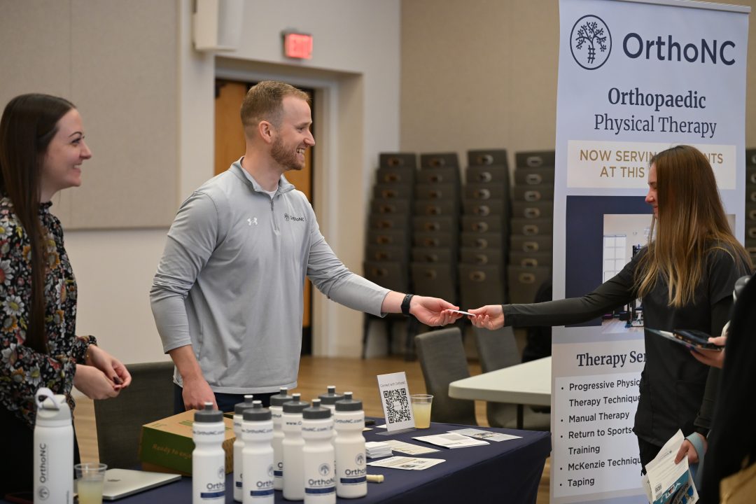 DPT alumnus handing materials to a current student.
