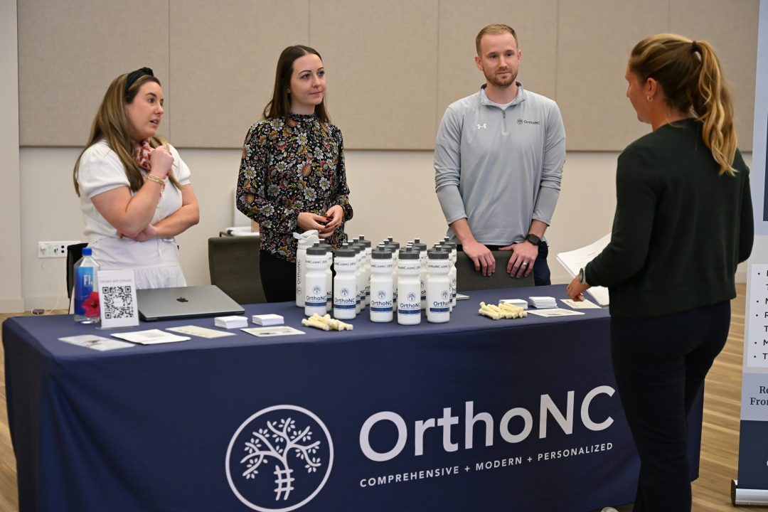DPT alumnus and his coworkers talking with student.