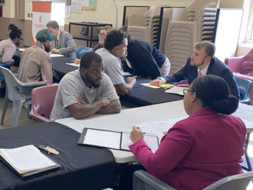 Photo from Blanchard Community Law Clinic's Driver's License Restoration event at Sampson Correctional Facility showing folks filling out paperwork