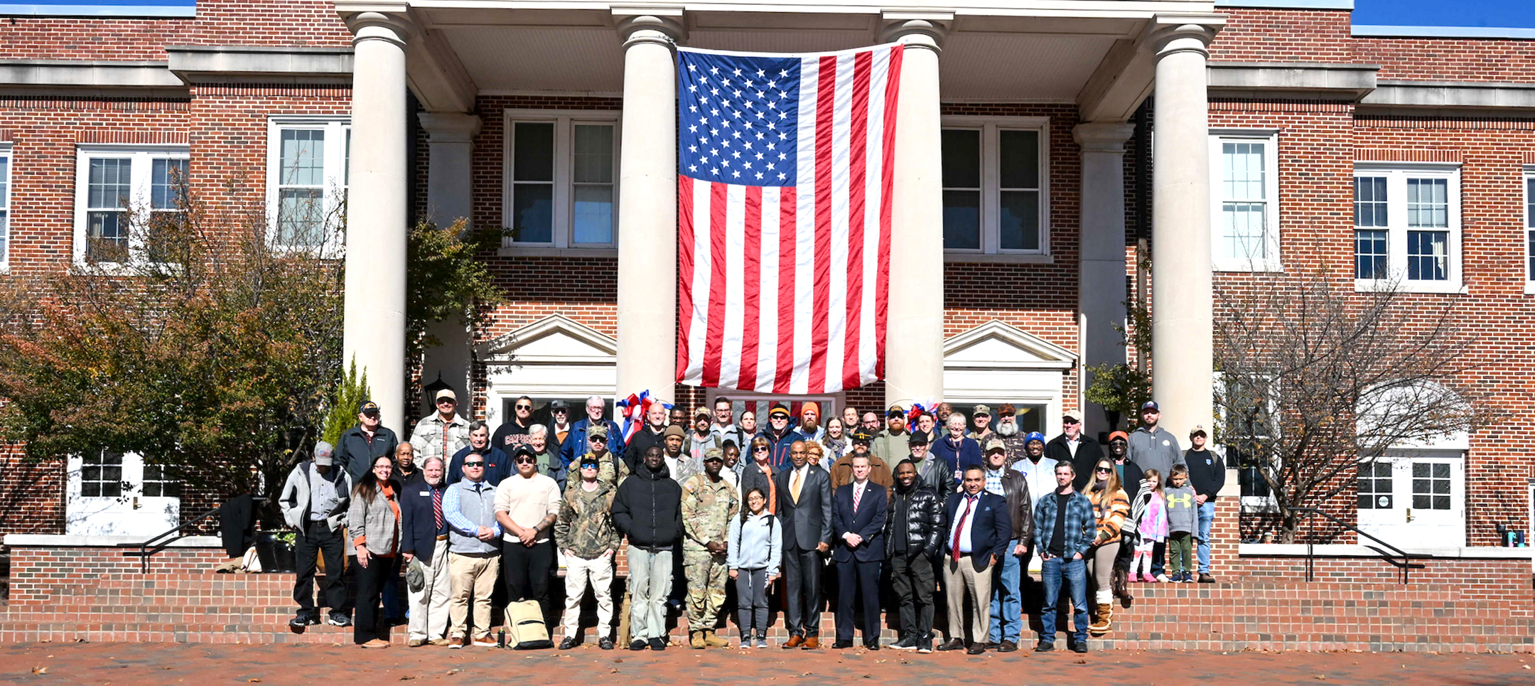 Group photo on veterans day ceremony. Standing in front of American flag.