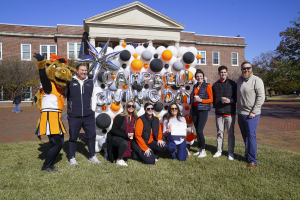 Campbell staff posing in front of Campbell Giving Day balloon art sign