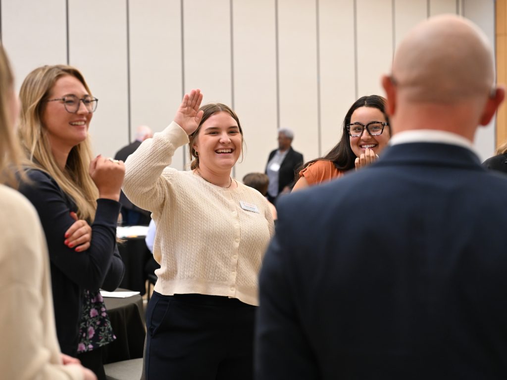Student raising hand in group.