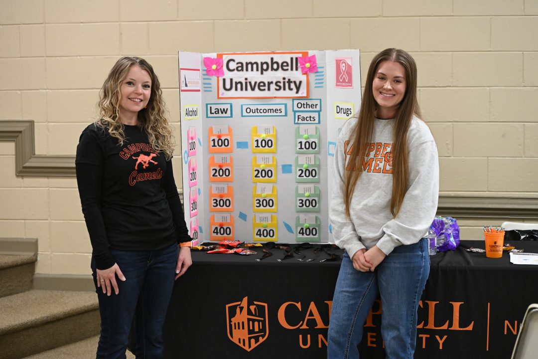 Faculty member and student standing with materials.