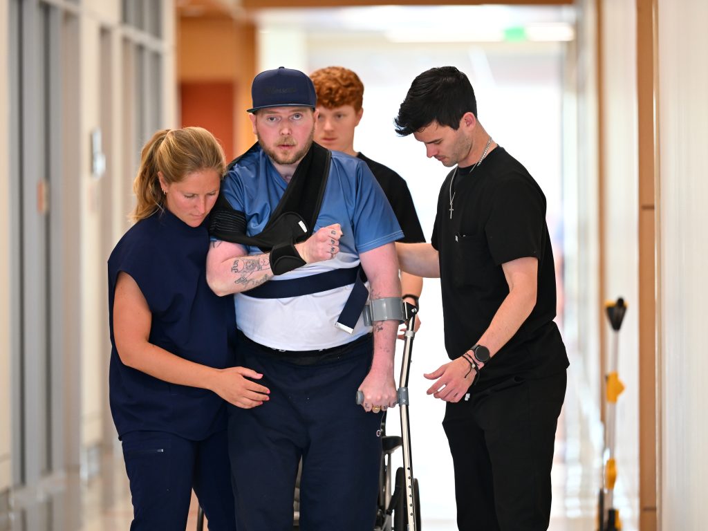 Anna Fish supporting patient walking down the hallway.