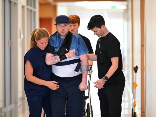 Anna Fish supporting patient walking down the hallway.