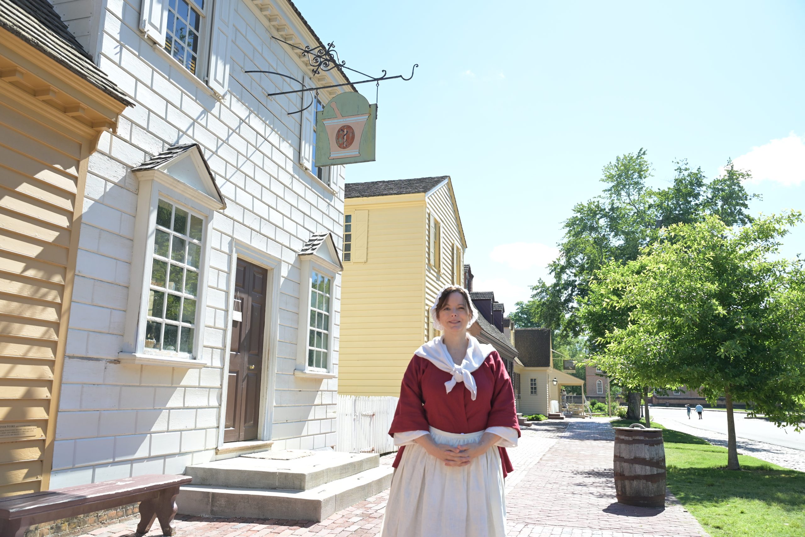 Susan Propst standing in front of the apothecary at Colonial Williamsburg wearing period clothing.