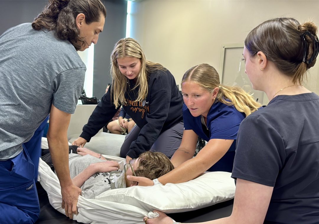 Anna Fish stabilizes a patient's head during lab.