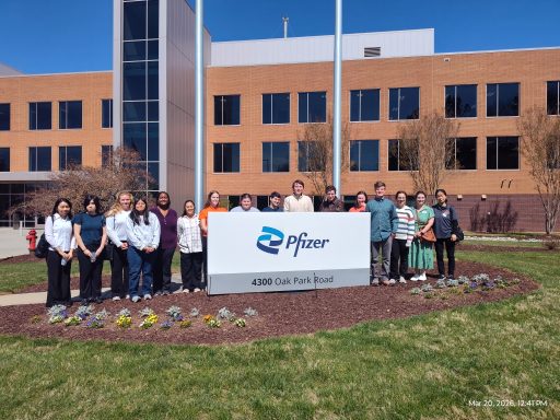 Pharmaceutical & Clinical Sciences undergrad students with faculty chaperone stand with the Pfizer sign