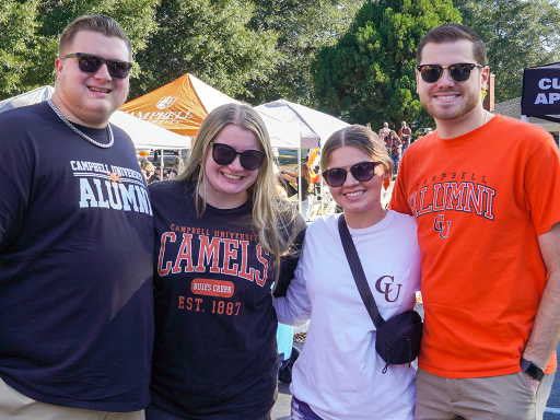 Four people standing next to each other wearing sunglasses and Campbell Alumni or Campbell University t-shirts