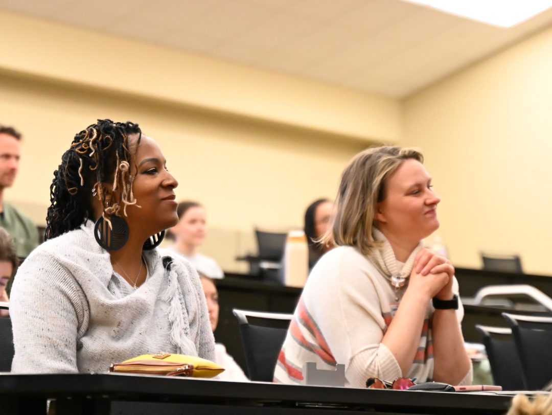 Two female attendees looking at the panel