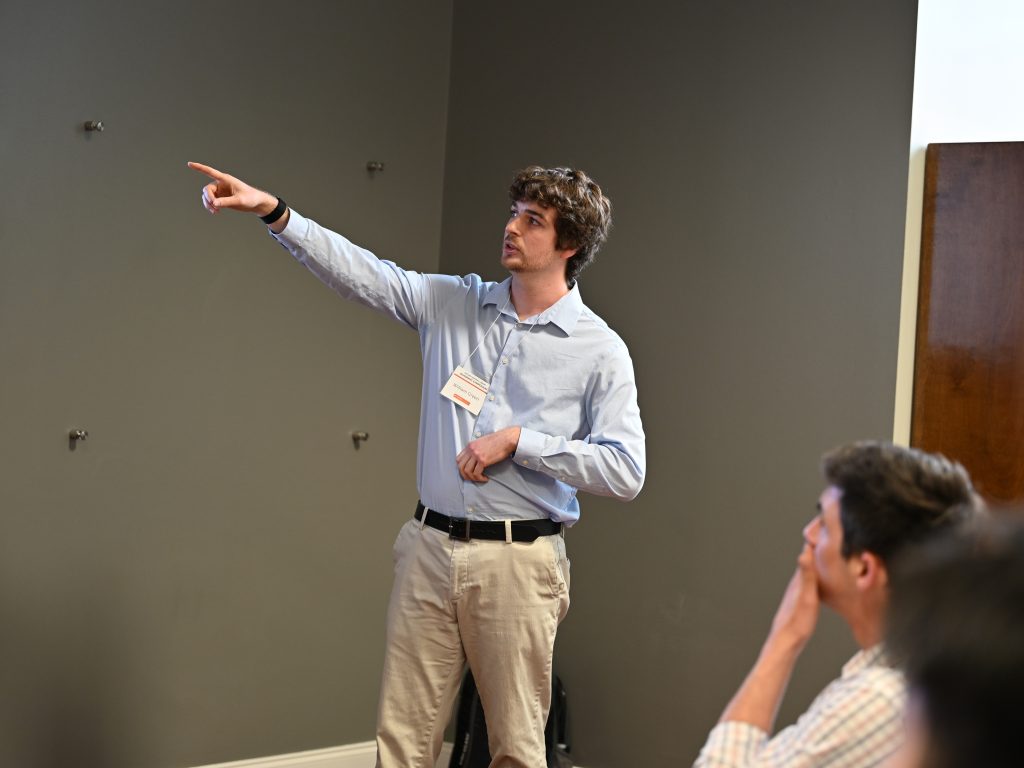 Male student in blue shirt points to the screen during his presentation