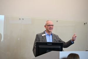 Dr. Jeff Mercer, dean of CPHS, addresses a group while standing at the podium.