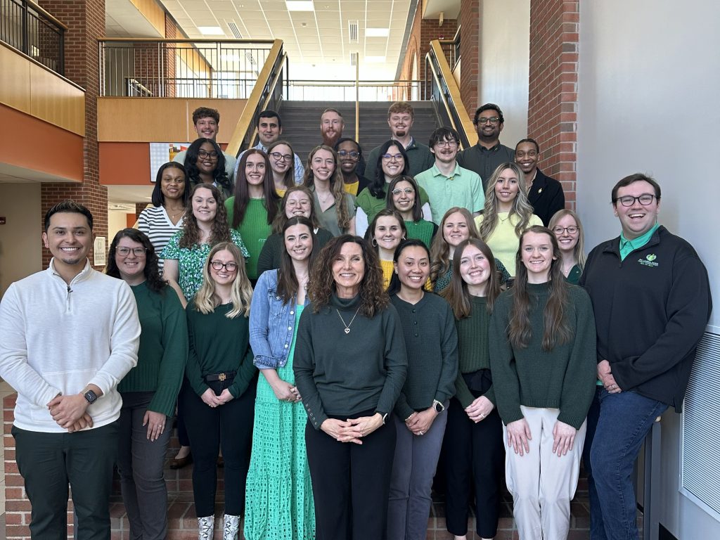 2026 chapter inductees standing on the staircase of Maddox Hall with faculty advisor, Dr. Beth Mills