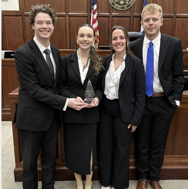 Photo of four Campbell Law advocates holding AAJ STAC national championship trophy in courtroom in New Orleans