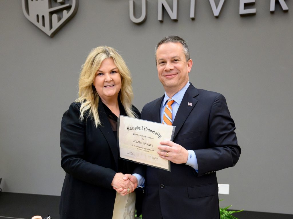 Female honoree stands with University President holding a certificate