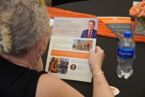 A person is reading a piece of paper with information about the Wiggins Society on it.