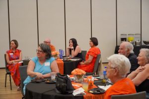 A group of people sitting at tables looking forward.
