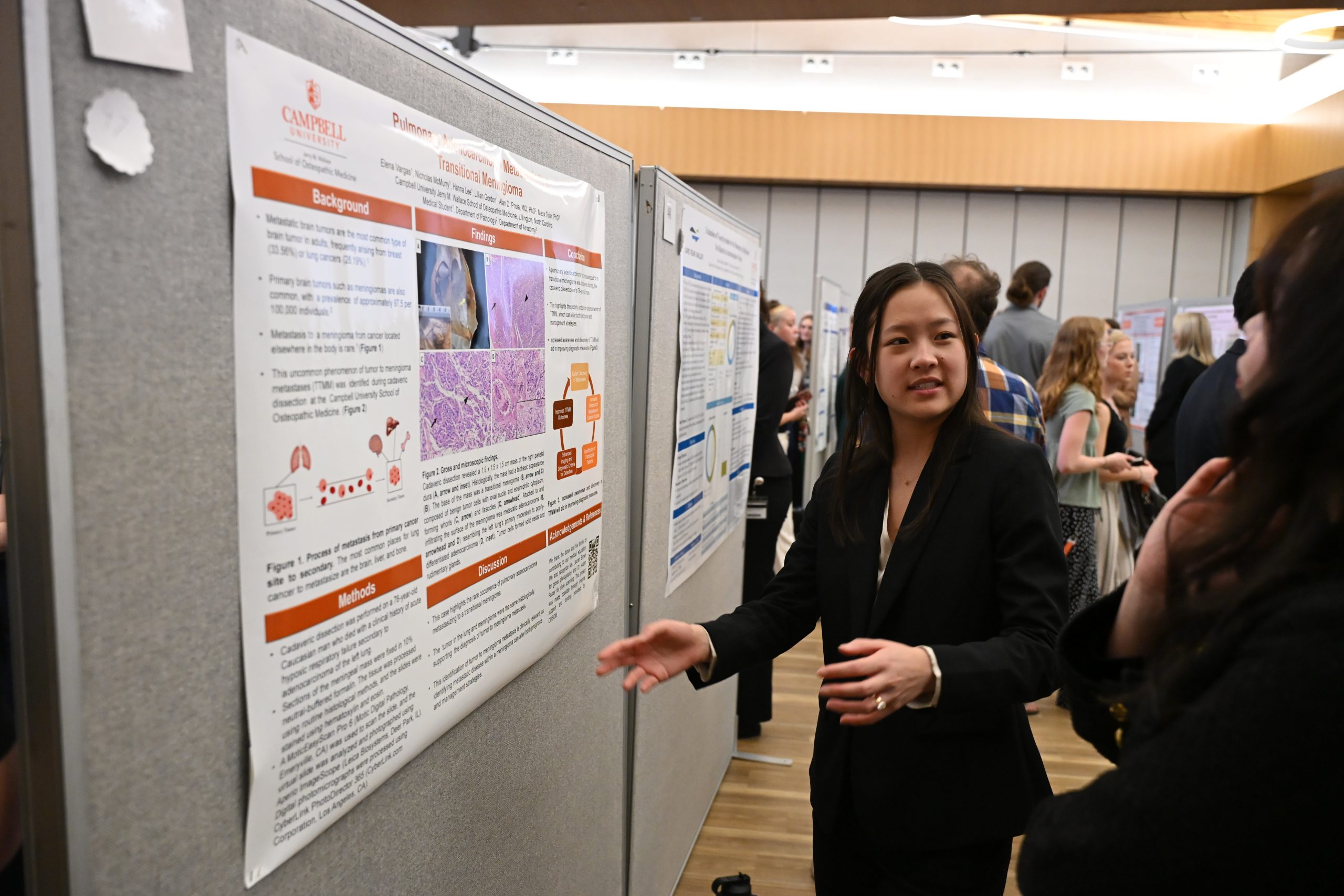 Female student gesturing to poster and talking with attendee