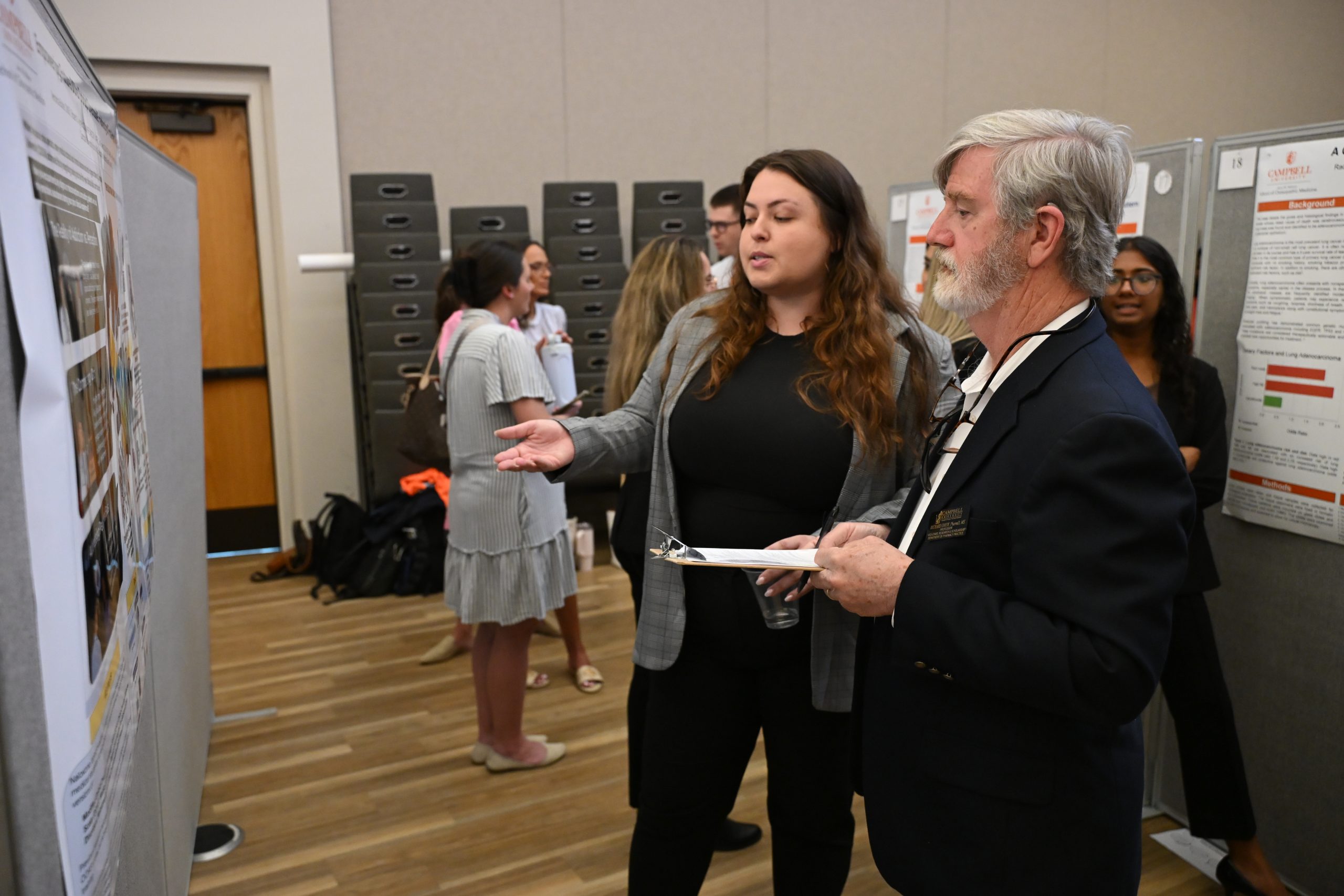 Male faculty member listening to female student present her poster