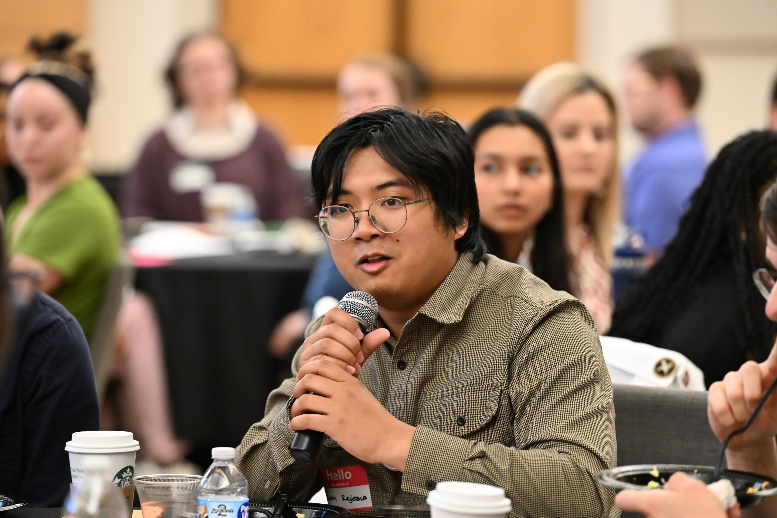 Asian male wearing glasses and holding a microphone