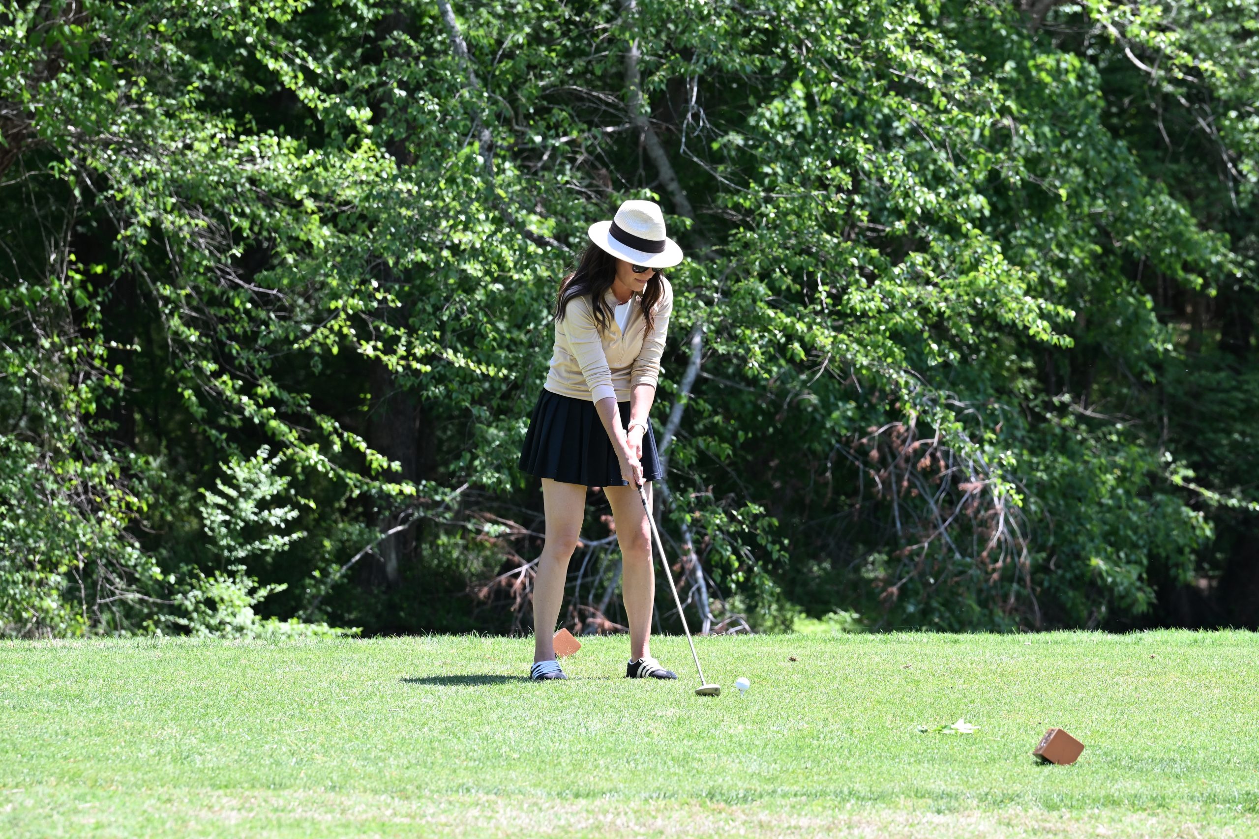 Female golfer in fedora hat ready to drive the ball