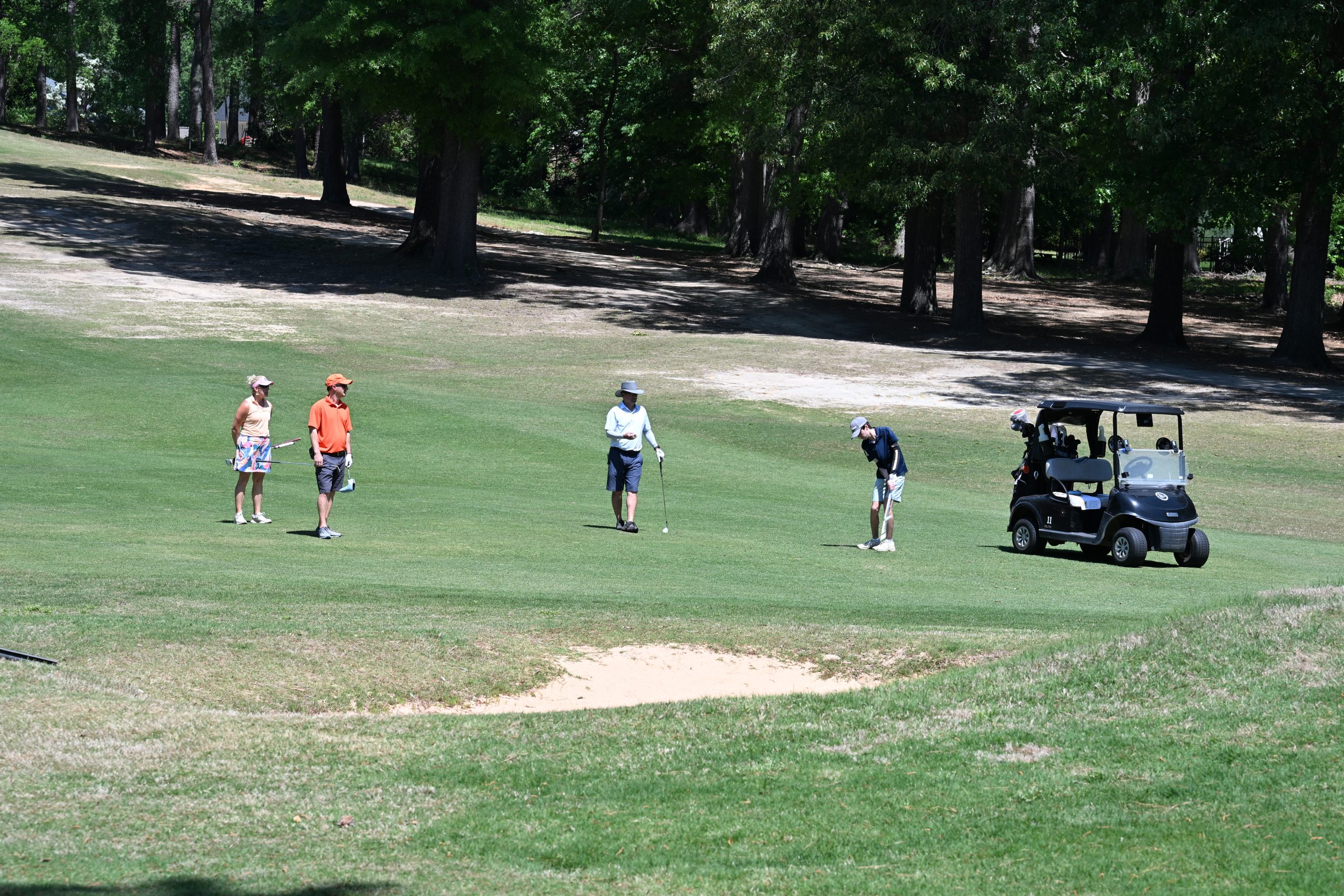 Team of four golfers with a golf cart