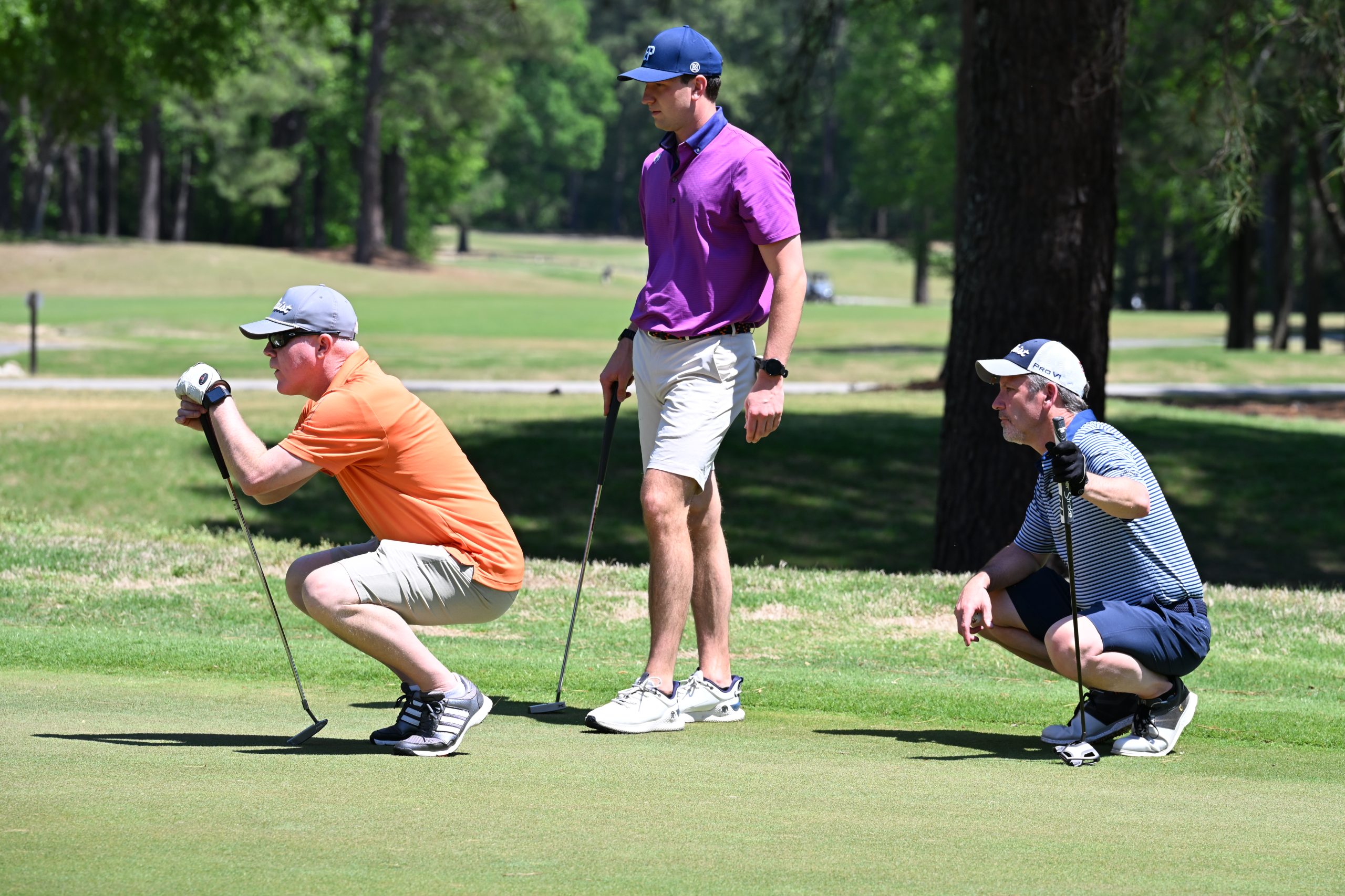 Three male golfers looking to line up their shots