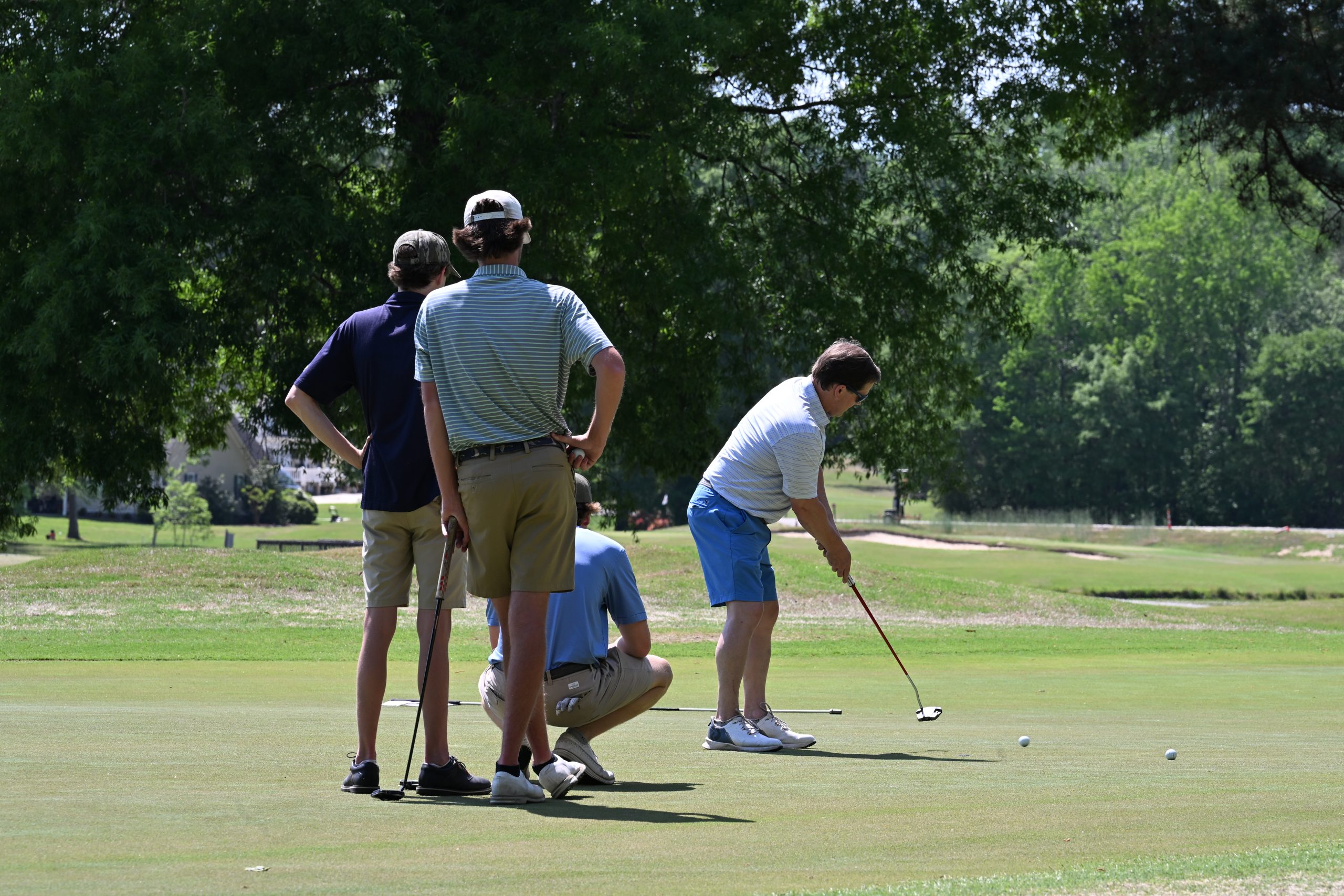 Team of three golfers watch the fourth putt