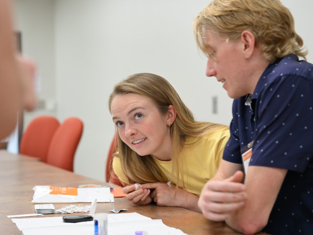 Female wearing yellow shirt looking up at faculty member