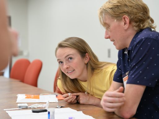 Female wearing yellow shirt looking up at faculty member