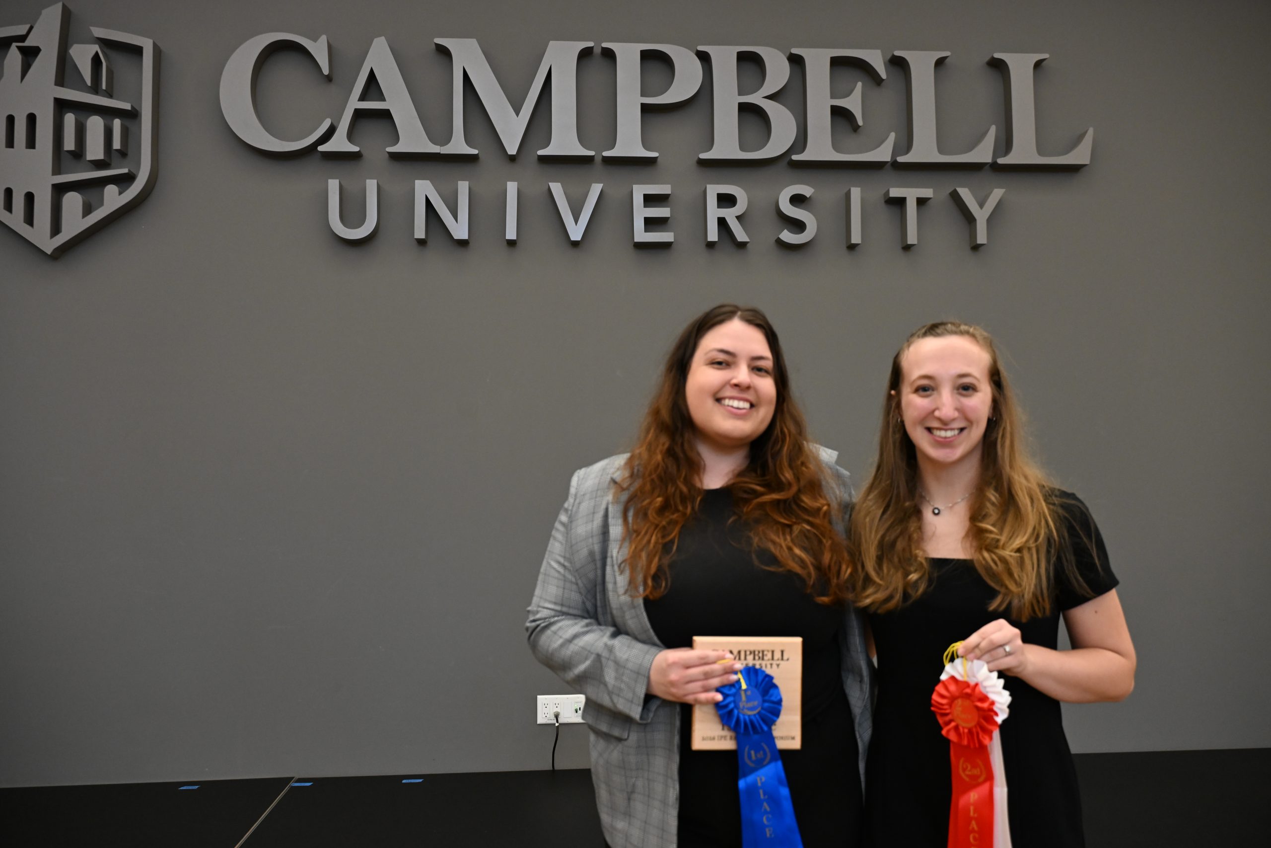 two female students holding award ribbons